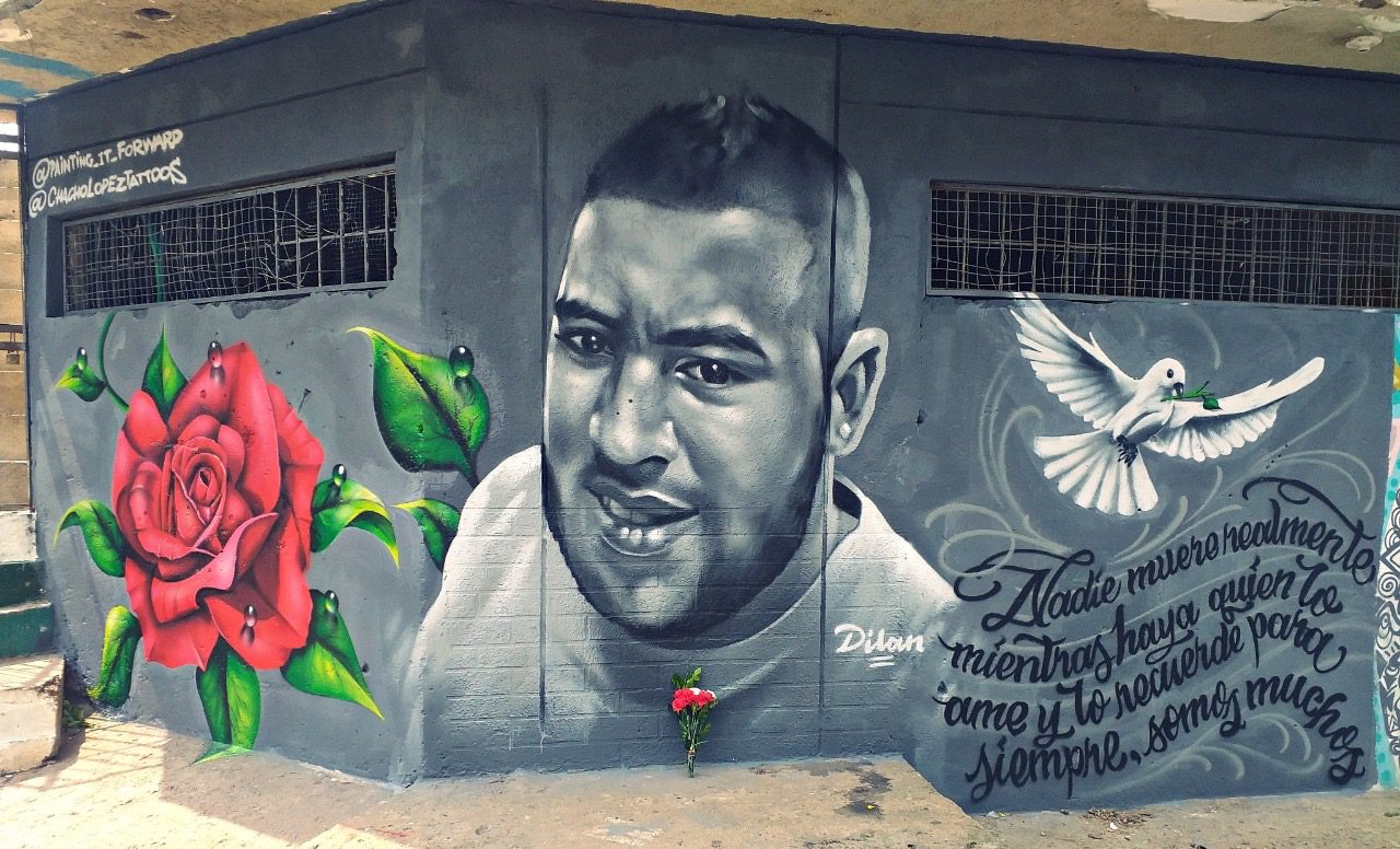 A mural of a man with roses and dove on the side.