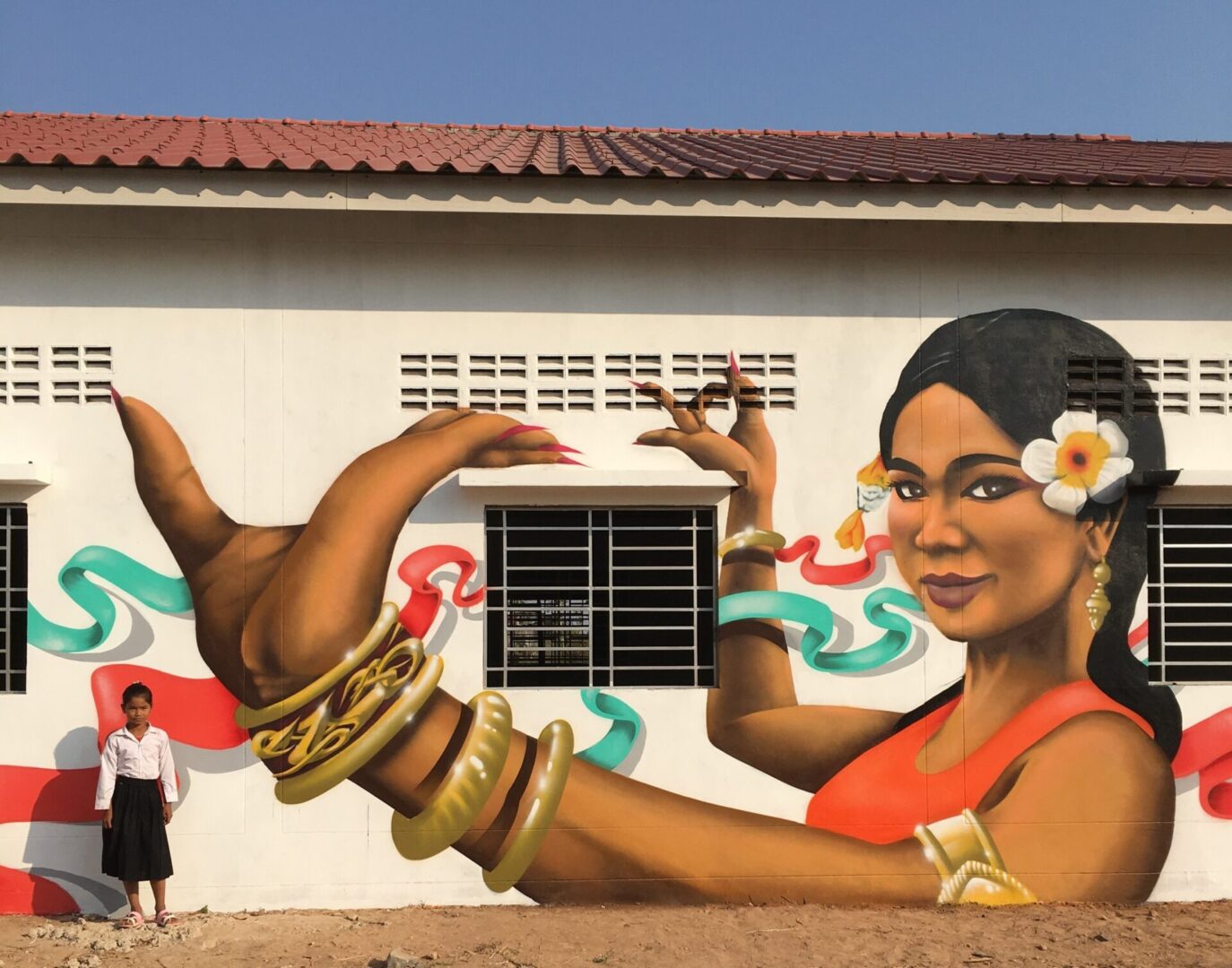 A woman standing in front of a mural on the side of a building.