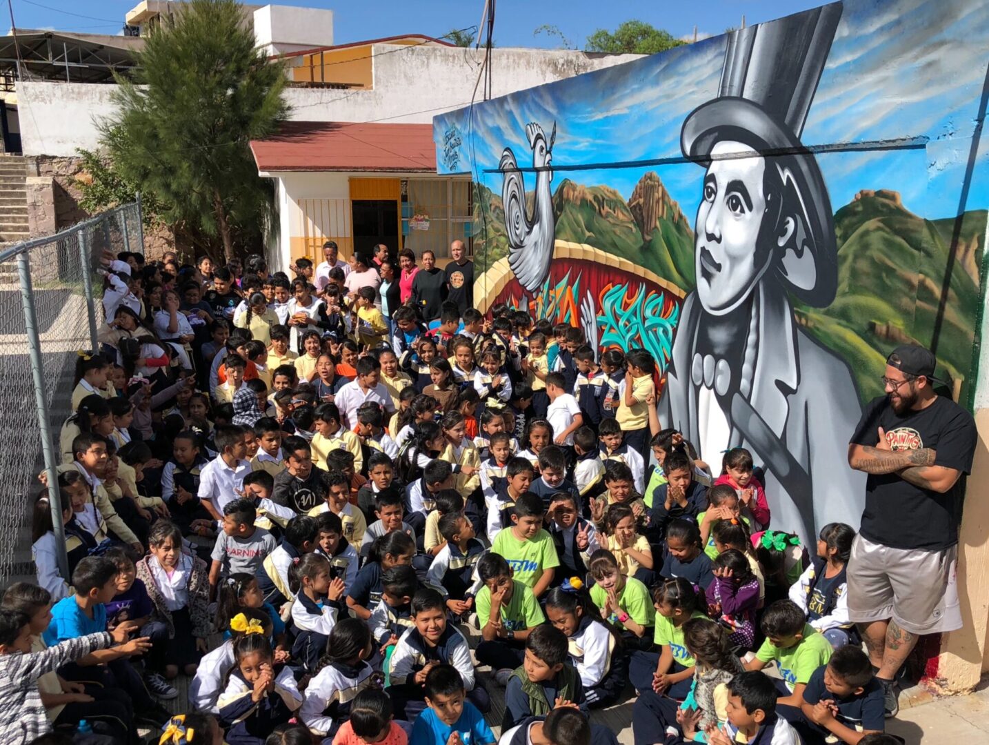 A crowd of people standing in front of a mural.