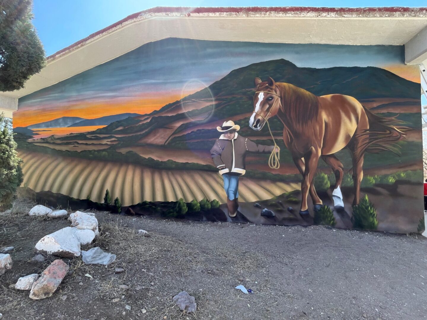 A mural of a man and horse in the middle of a field.