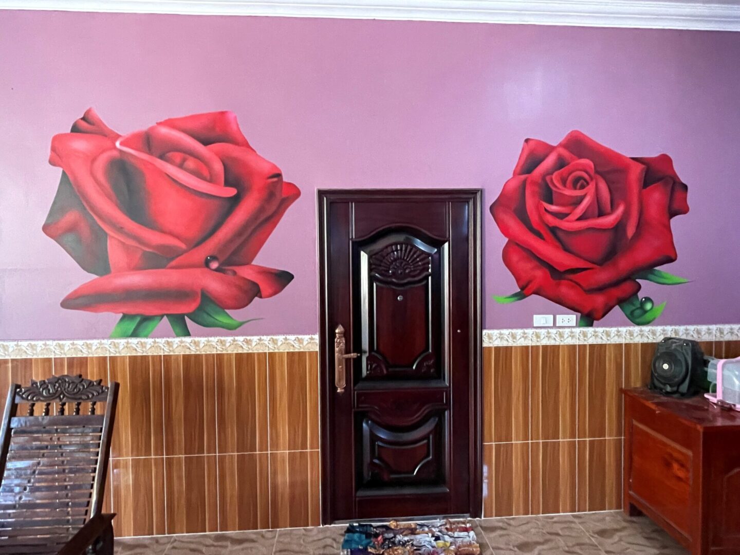 A door with two roses on it in the corner of a room.