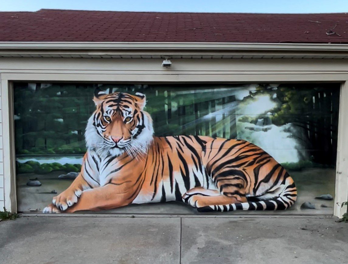 A painting of a tiger sitting on the side of a building.