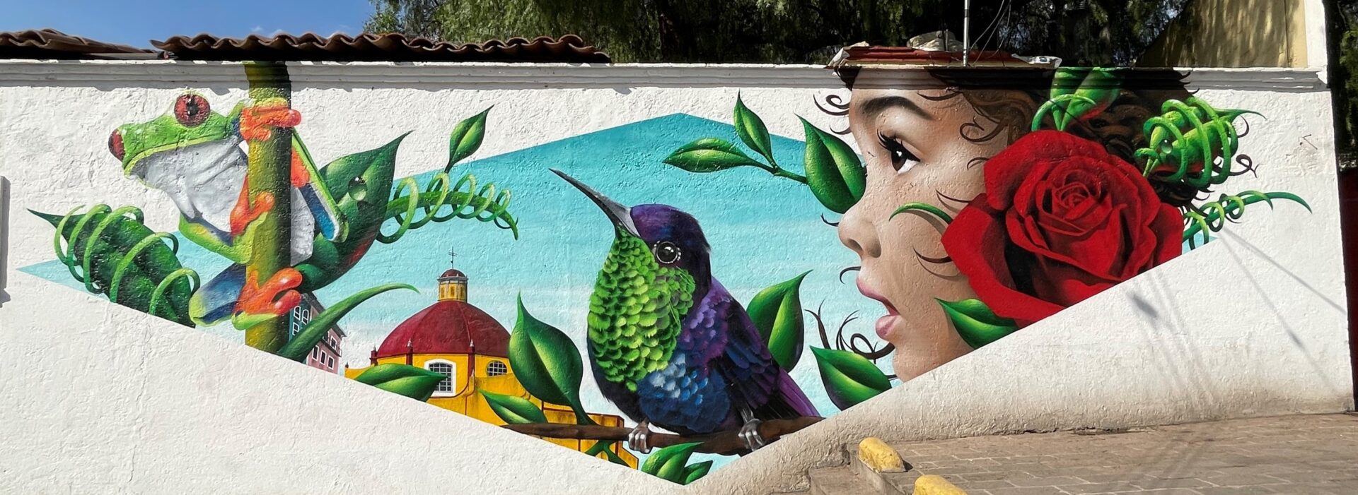 A mural of a girl and hummingbird on the side of a building.