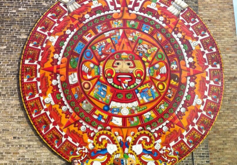 A large colorful mural of an aztec calendar.